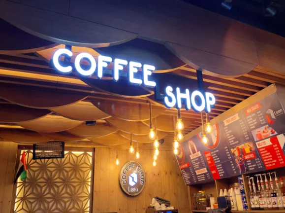 Modern illuminated lettering inside the Coffee Shop Leen with wooden ceiling.
