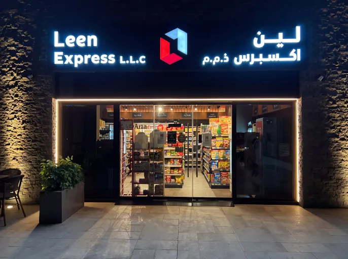 Brightly lit shopfront sign for Leen Express with illuminated border and letters.