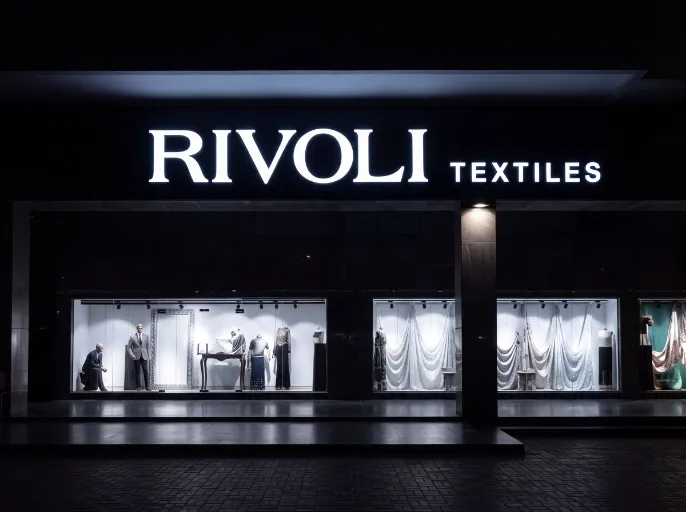 Large illuminated front-lit channel letters for Rivoli Textiles at night.